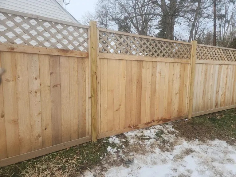 Six-foot cedar privacy fence with a lattice top section installed along a side yard in Wynnewood, PA, with snow on the ground